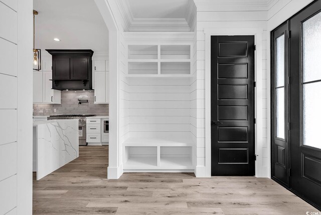 kitchen with crown molding, a healthy amount of sunlight, dark brown cabinetry, and light stone countertops