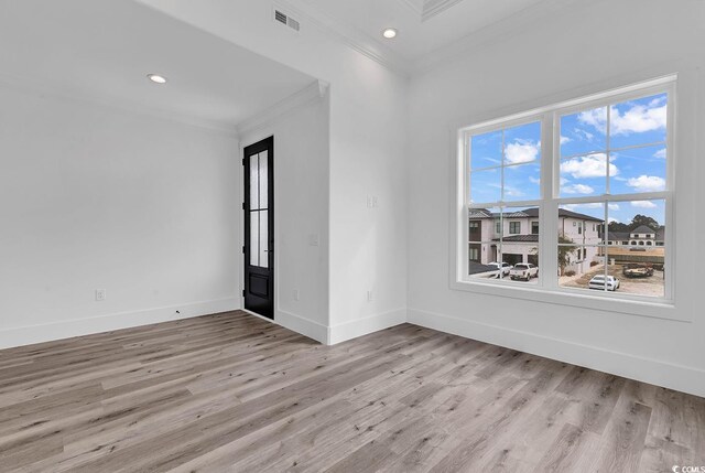 empty room featuring ornamental molding, wooden walls, a notable chandelier, and light wood-type flooring