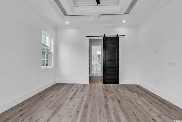 unfurnished room featuring crown molding, a barn door, coffered ceiling, and light hardwood / wood-style floors