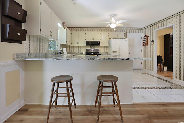 kitchen with ceiling fan, light wood-type flooring, white fridge with ice dispenser, and stove