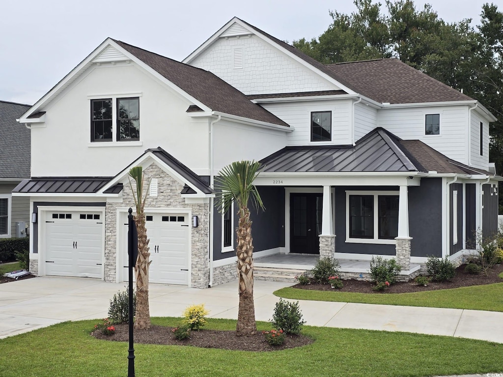 view of front of property with a front yard, a garage, and a porch