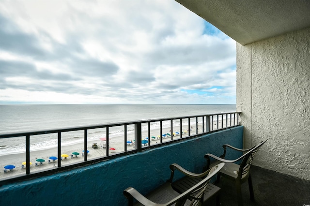 balcony featuring a view of the beach and a water view