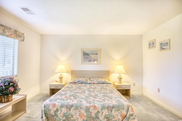 bedroom with light colored carpet and a textured ceiling