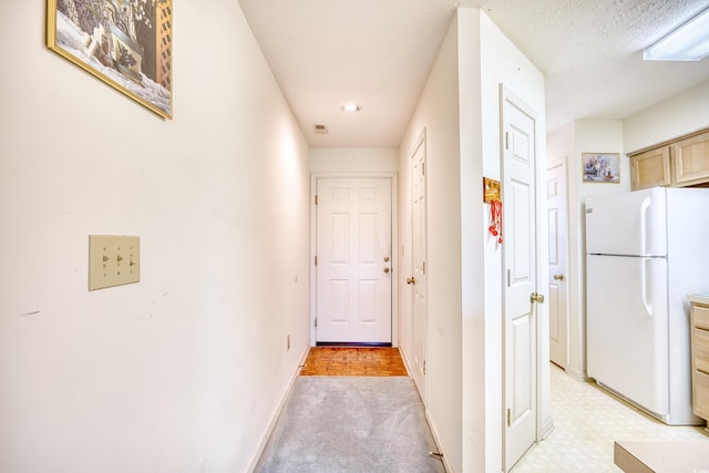 corridor with a textured ceiling and light carpet