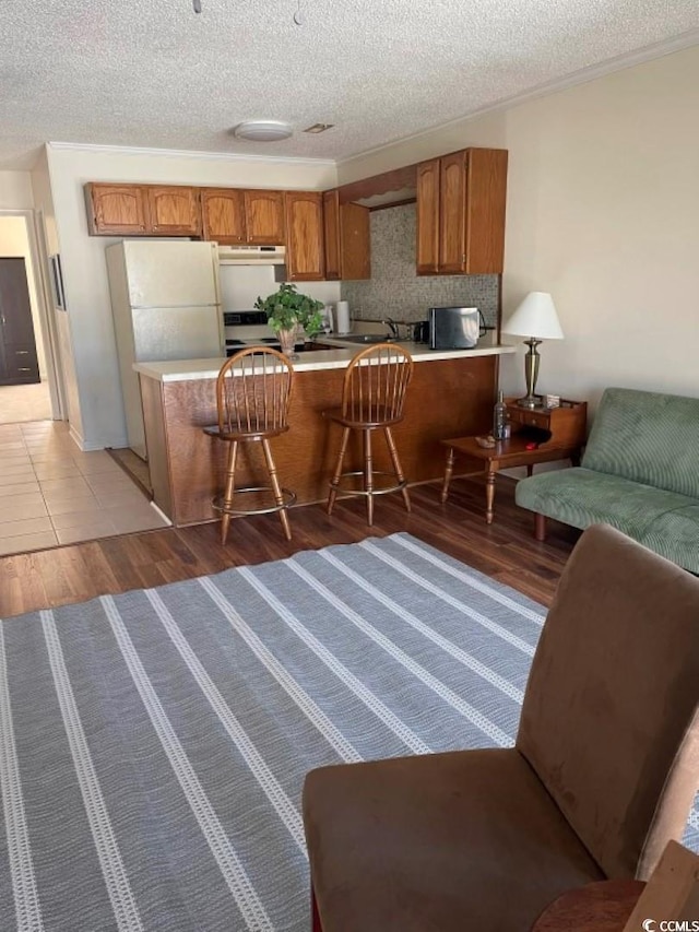 interior space featuring a textured ceiling, kitchen peninsula, hardwood / wood-style floors, and white appliances