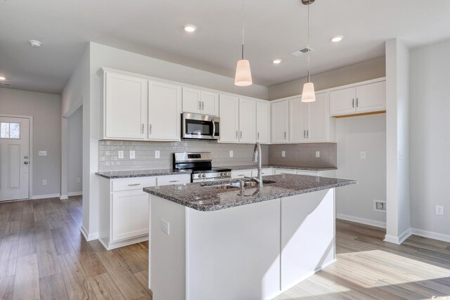 kitchen featuring appliances with stainless steel finishes, sink, an island with sink, white cabinets, and dark hardwood / wood-style flooring