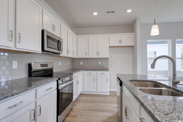 kitchen featuring hardwood / wood-style floors, sink, appliances with stainless steel finishes, a kitchen island with sink, and white cabinets