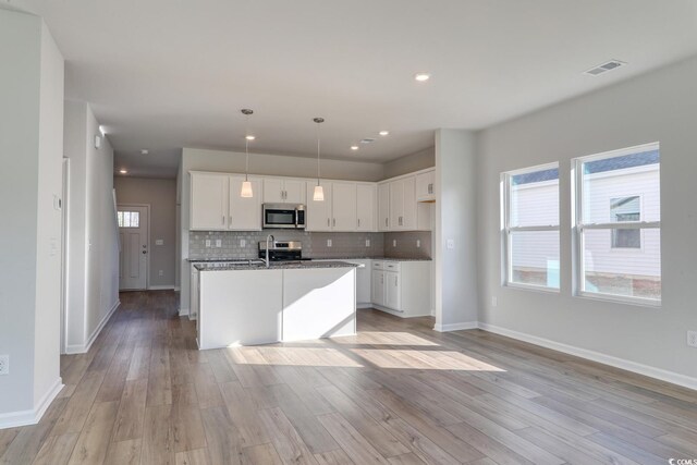 living room with a wealth of natural light, ceiling fan, ornamental molding, and wood-type flooring