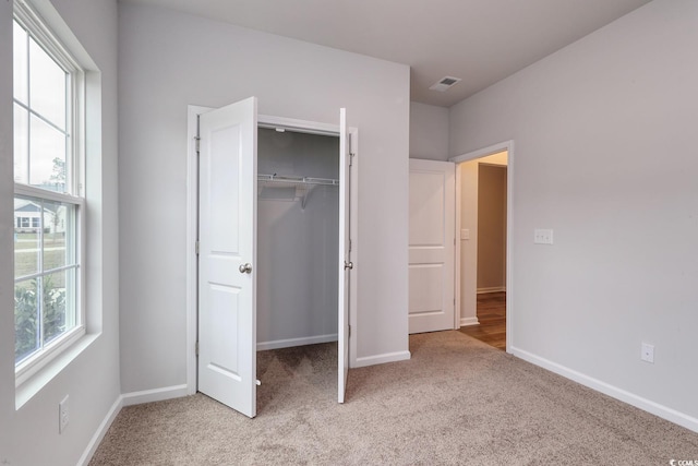 unfurnished bedroom with light carpet and a closet