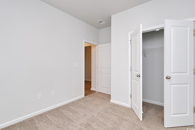 unfurnished bedroom with a closet and light colored carpet