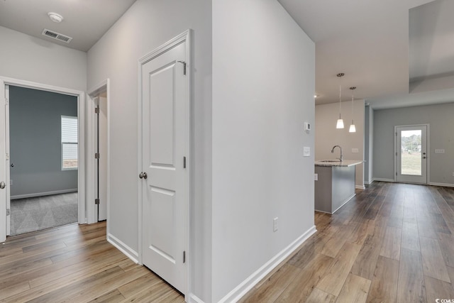 hallway with sink and light wood-type flooring