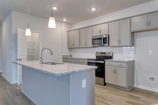 kitchen with stainless steel appliances, light hardwood / wood-style flooring, hanging light fixtures, and sink