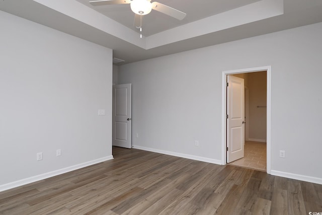 spare room featuring a raised ceiling, ceiling fan, and hardwood / wood-style flooring