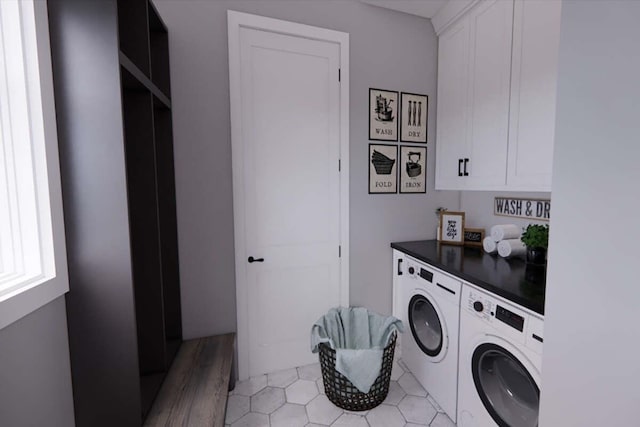 laundry area with light wood-type flooring, washing machine and clothes dryer, and cabinets