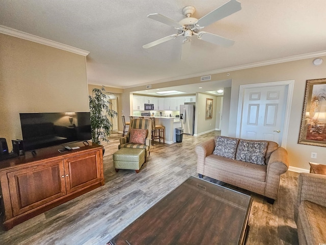 living room featuring hardwood / wood-style flooring, crown molding, and ceiling fan