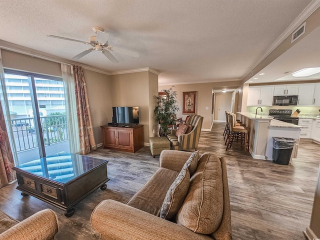 living room with ornamental molding, wood-type flooring, and a textured ceiling