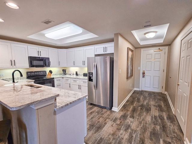 kitchen featuring white cabinets, a tray ceiling, kitchen peninsula, and black appliances