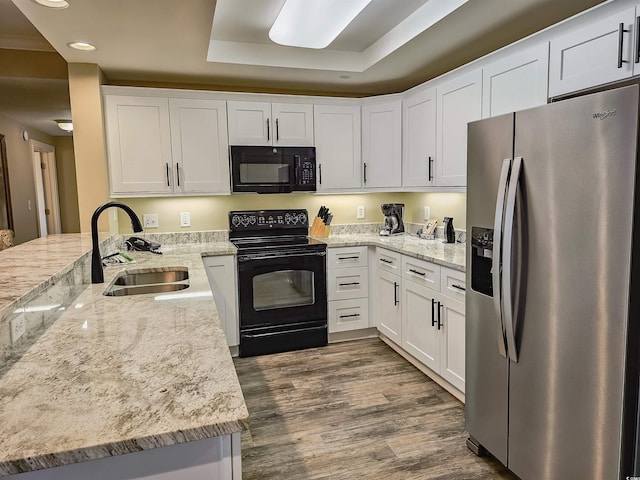 kitchen featuring sink, white cabinets, black appliances, a raised ceiling, and light stone countertops