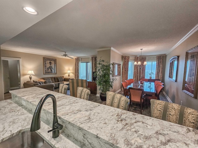 dining area with ornamental molding, a wealth of natural light, ceiling fan with notable chandelier, and a textured ceiling