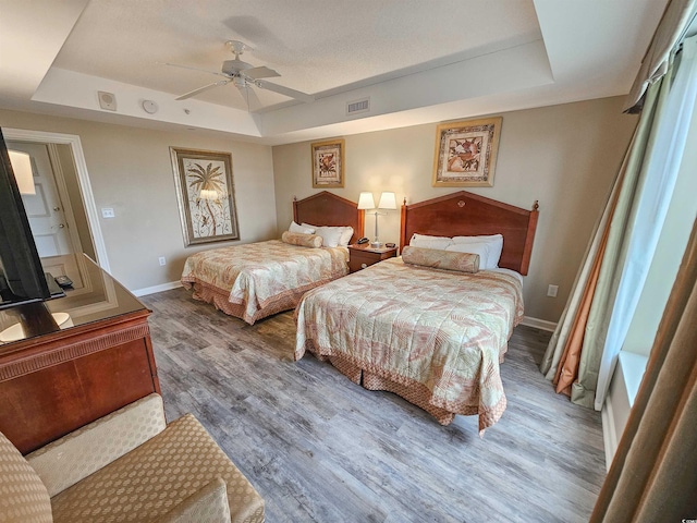 bedroom featuring ceiling fan, a tray ceiling, and hardwood / wood-style floors