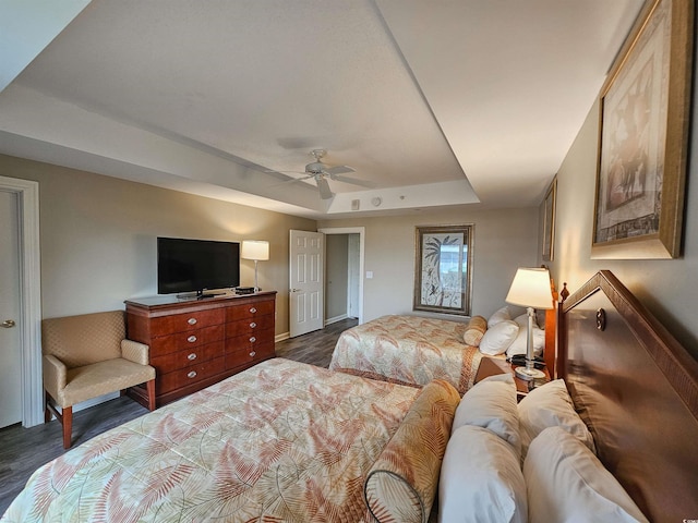 bedroom featuring ceiling fan, dark hardwood / wood-style flooring, and a tray ceiling