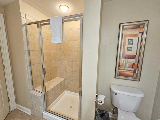 bathroom featuring a shower with door, tile patterned floors, and toilet