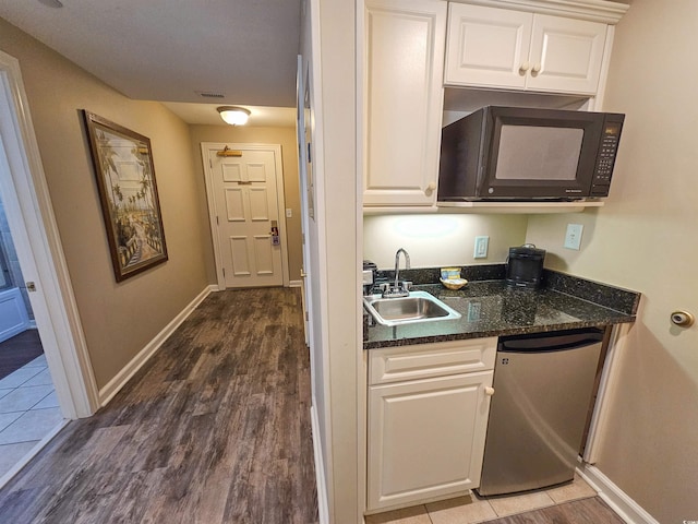 kitchen featuring sink, white cabinetry, dark stone countertops, dark hardwood / wood-style flooring, and dishwashing machine