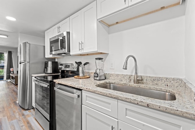 kitchen featuring light stone counters, sink, white cabinetry, appliances with stainless steel finishes, and light wood-type flooring