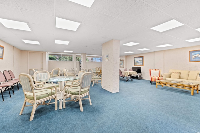 carpeted dining space with a drop ceiling