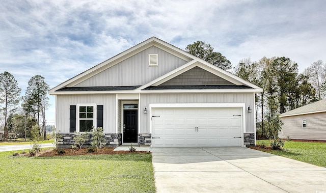 view of front of home with driveway, stone siding, an attached garage, and a front lawn