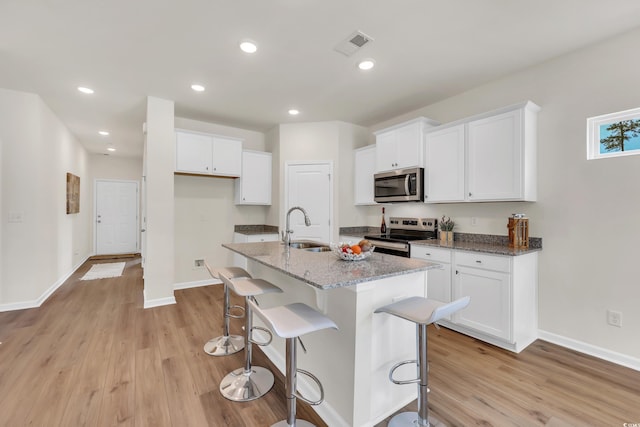 kitchen featuring a sink, stainless steel appliances, light wood finished floors, and white cabinetry