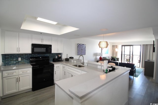 kitchen featuring black appliances, kitchen peninsula, sink, a tray ceiling, and white cabinetry