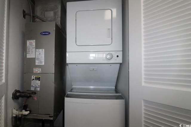 laundry room featuring heating unit and stacked washer and clothes dryer