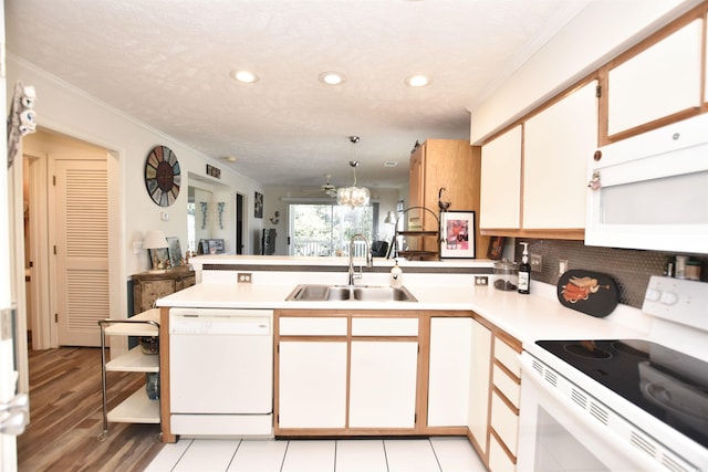 kitchen featuring white cabinetry, white appliances, kitchen peninsula, sink, and hanging light fixtures