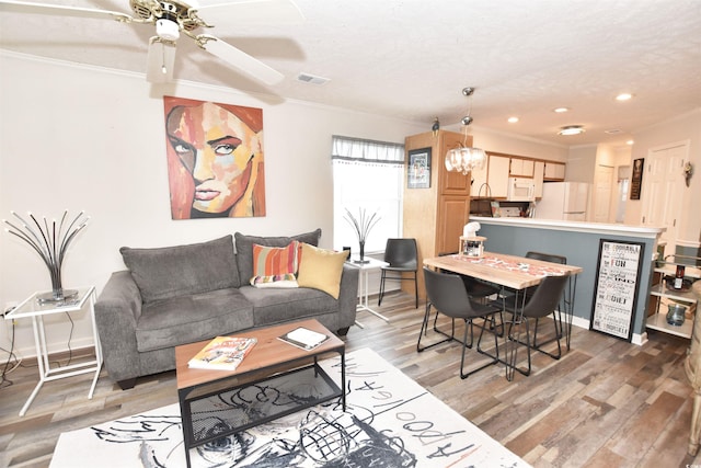 living room with hardwood / wood-style floors, ceiling fan, a textured ceiling, and ornamental molding