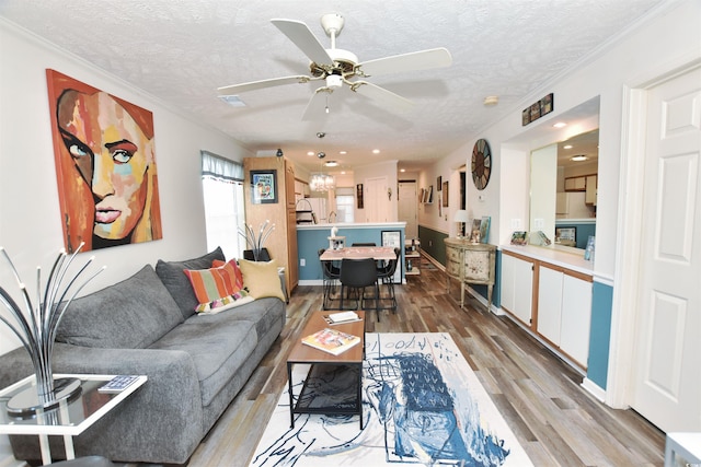 living room featuring ceiling fan, hardwood / wood-style flooring, crown molding, and a textured ceiling