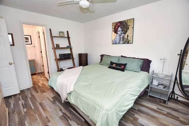 bedroom with a textured ceiling, ceiling fan, and dark hardwood / wood-style floors