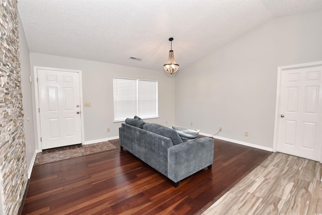 living area featuring baseboards, wood finished floors, an inviting chandelier, vaulted ceiling, and a textured ceiling