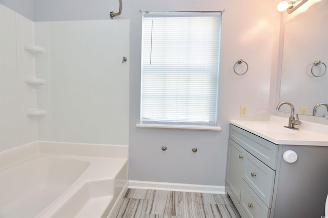 full bath with a bathtub, vanity, and baseboards