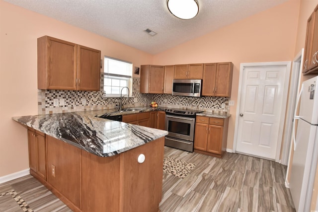 kitchen featuring a peninsula, appliances with stainless steel finishes, and brown cabinetry