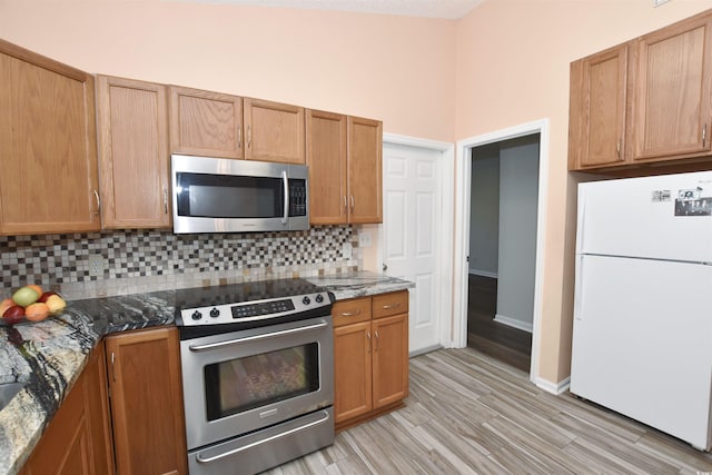 kitchen with dark stone counters, appliances with stainless steel finishes, and tasteful backsplash