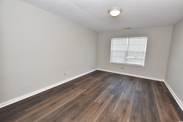 unfurnished room featuring visible vents, a textured ceiling, baseboards, and dark wood-style flooring