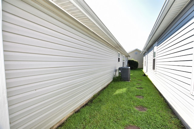 view of side of home featuring central AC and a yard