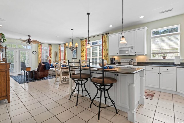 kitchen featuring white cabinets, hanging light fixtures, white appliances, and a kitchen island