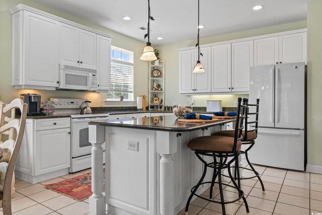 kitchen featuring white cabinets, light tile patterned flooring, white appliances, and hanging light fixtures