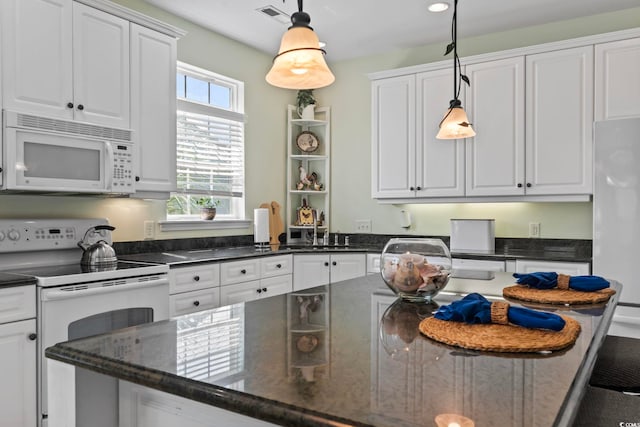 kitchen featuring sink, white appliances, white cabinetry, hanging light fixtures, and dark stone counters