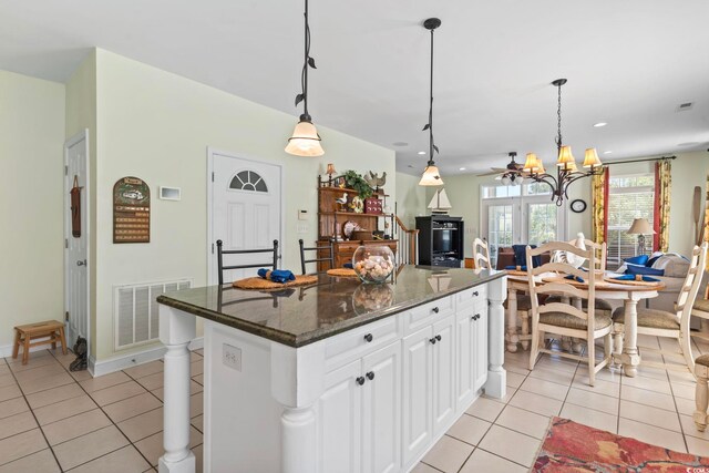 kitchen with white cabinets, a center island, light tile patterned floors, and hanging light fixtures