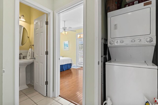 laundry room with ceiling fan, light wood-type flooring, and stacked washer / dryer