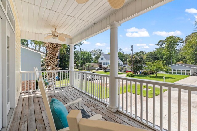 wooden terrace featuring ceiling fan, a yard, and covered porch