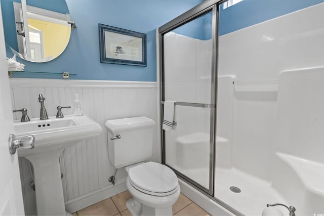 bathroom with a shower with door, sink, tile patterned floors, and toilet